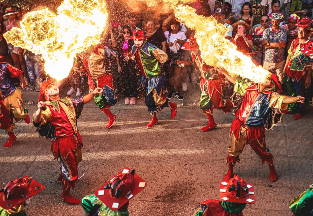 Colorful performers breathe fire during a lively street festival in Colombia, captivating audiences.