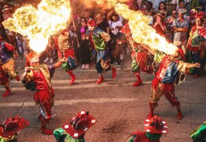 Colorful performers breathe fire during a lively street festival in Colombia, captivating audiences.